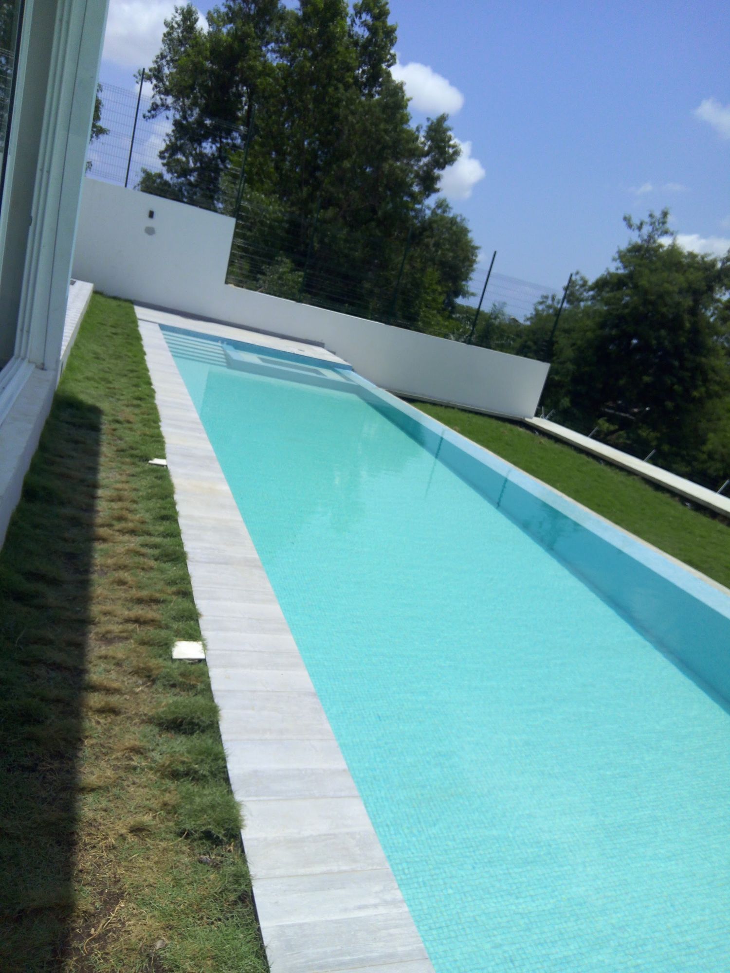 Le long couloir de nage de la piscine, bordé de gazon